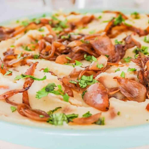 Mashed onions in a plate topped with green parsley.