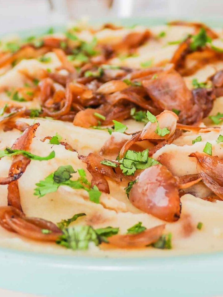 Mashed onions in a plate topped with green parsley.