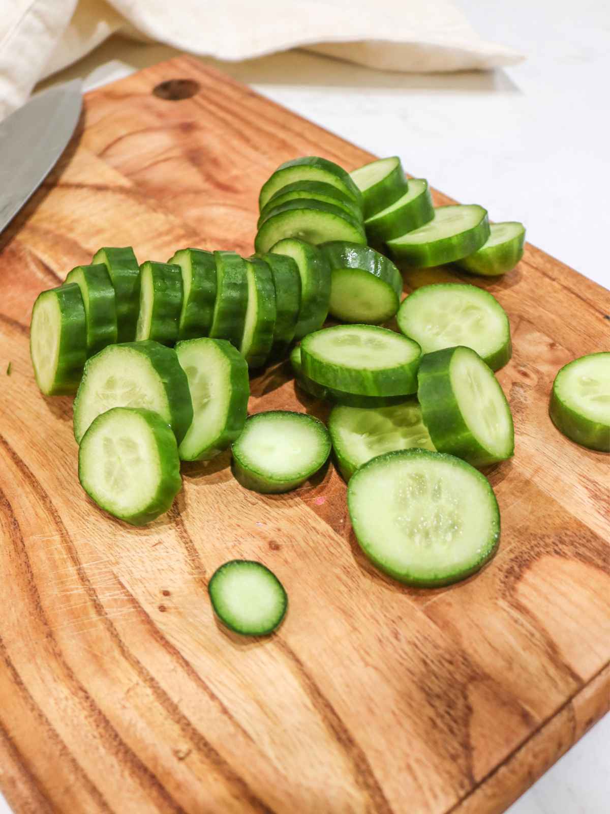 Sliced cucumbers on a wooden tray.