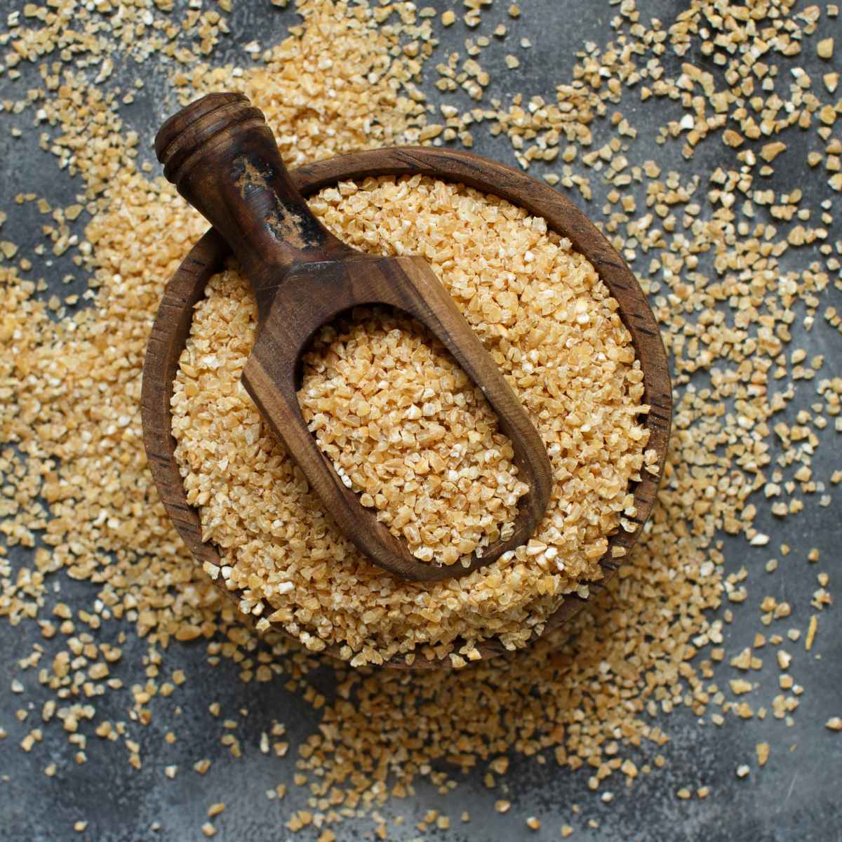 Bulgur wheat placed in w wooden bowl and wooden spoon.