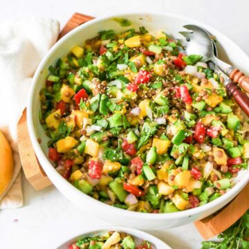 Mango cucumber salad served in a bowl placed on a wooden board and fork placed on side.