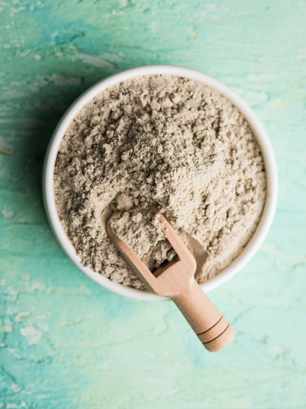 Millet flour in a white bowl and a wooden spoon palced on it