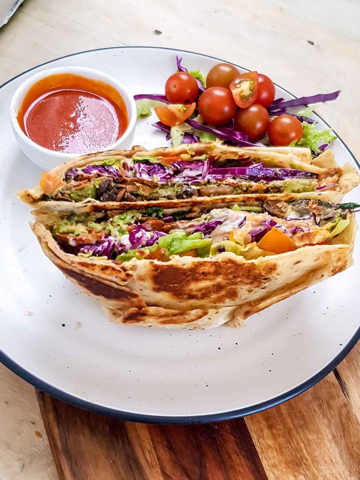 Crunch wrap supreme served in a white plate and salad on side.