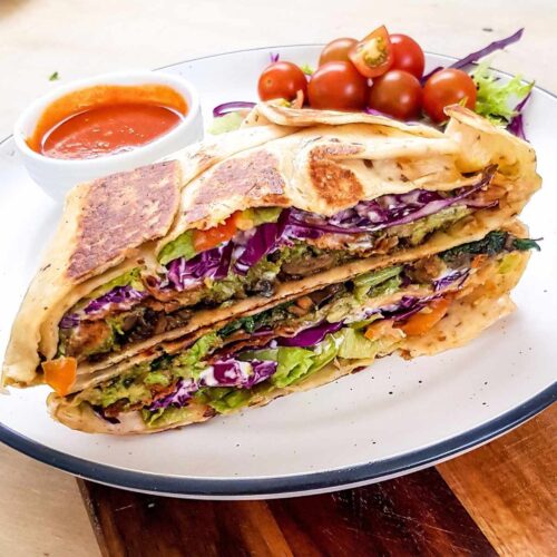 Mushroom crunch wrap supreme sliced in half and stacked on a plate.