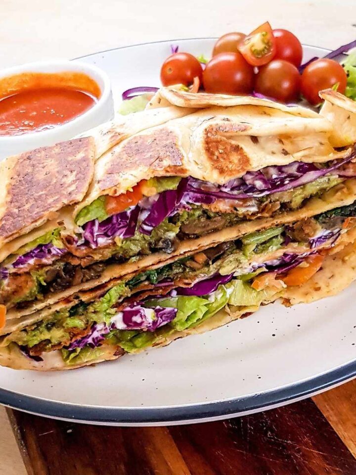 Mushroom crunch wrap supreme sliced in half and stacked on a plate.