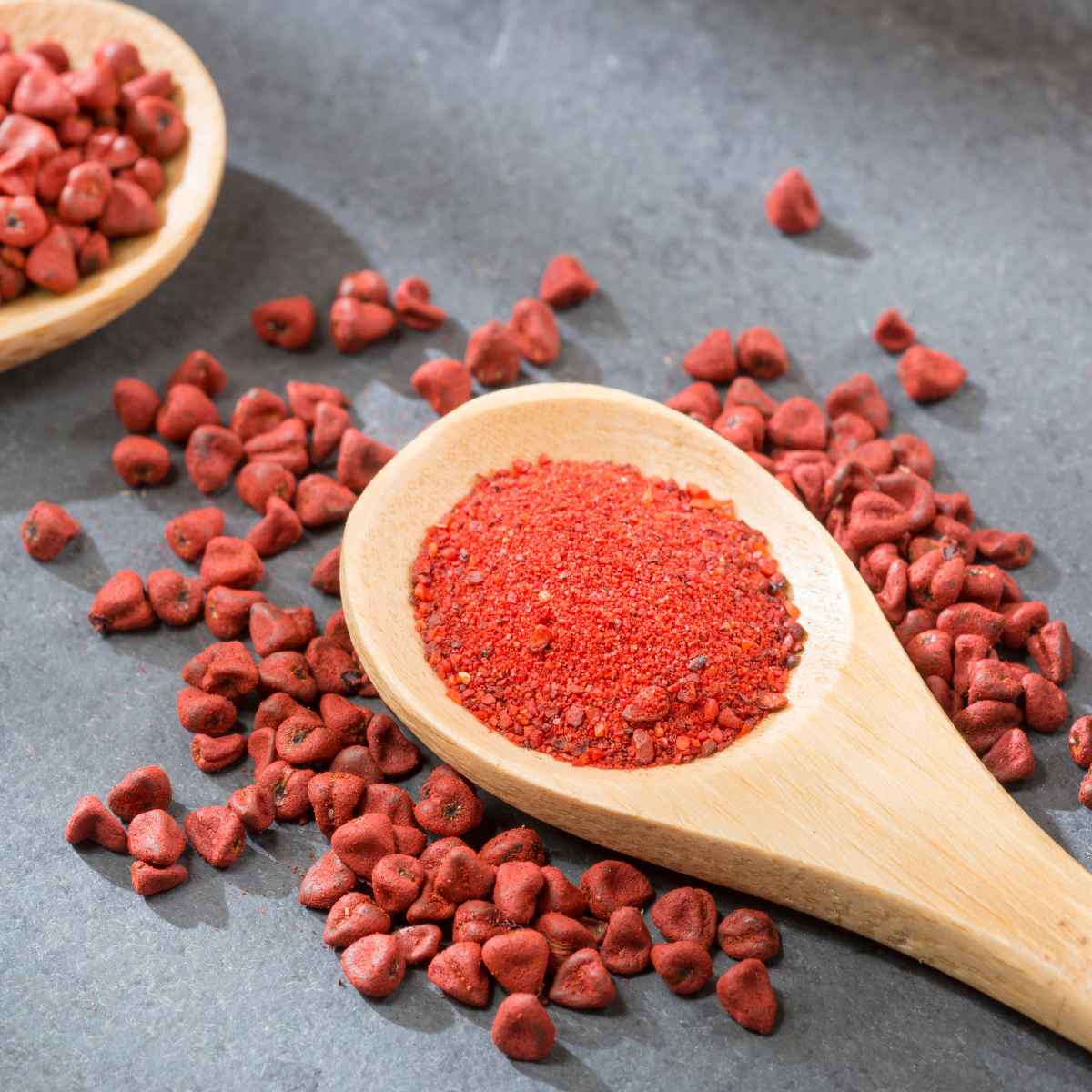 Annatto seeds powder on a wooden spoon.