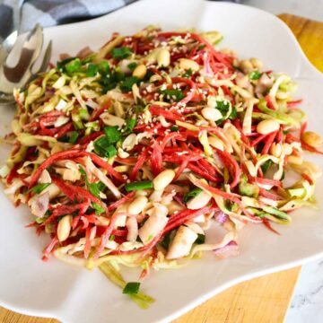 carrot cabbage salad topped with peanuts served on a white plate.