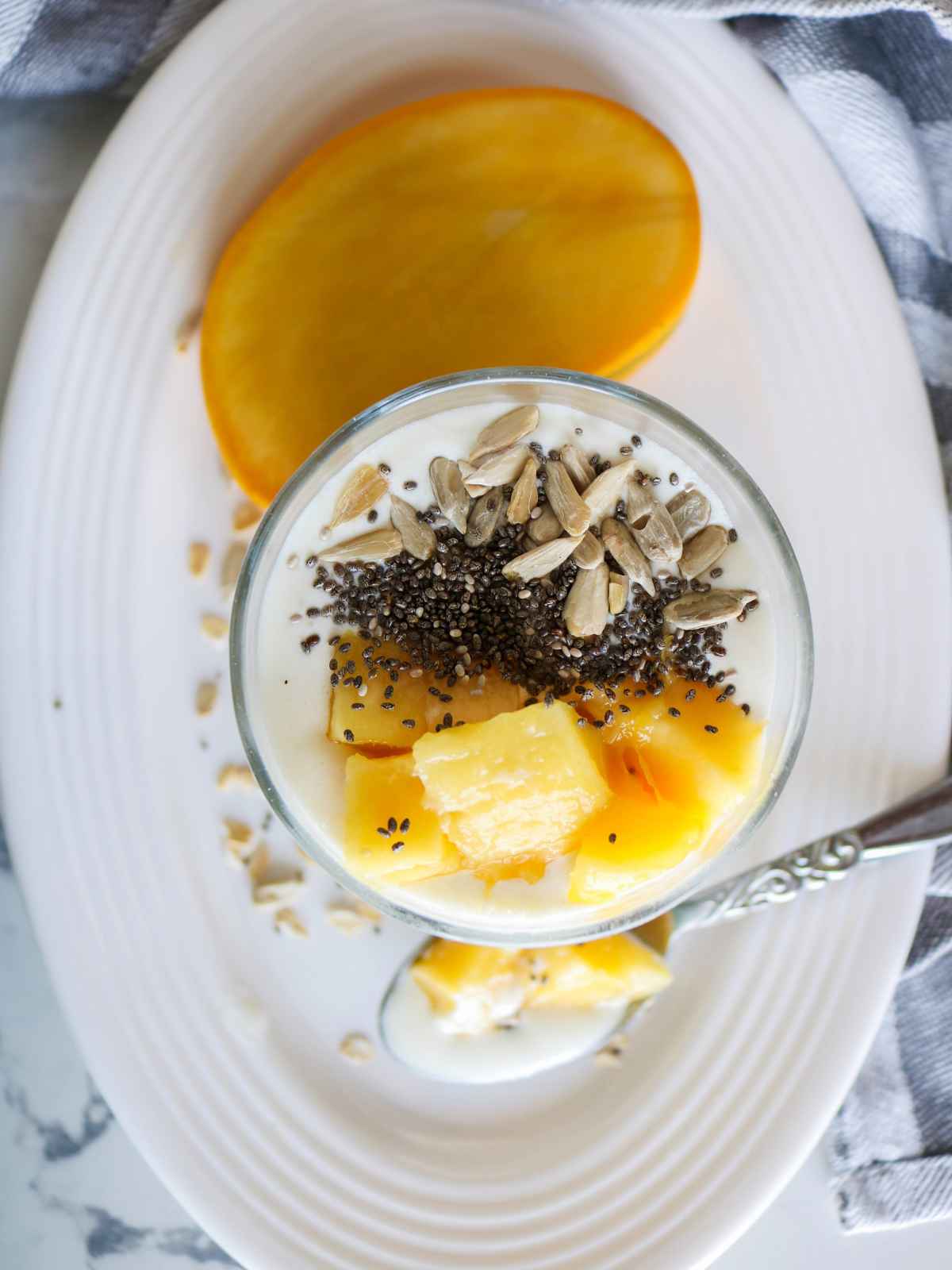Mango overnight oats served in a glass jar placed on a white dish.