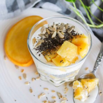 Overnight oats served in a glass jar topped with mango and chia seeds.