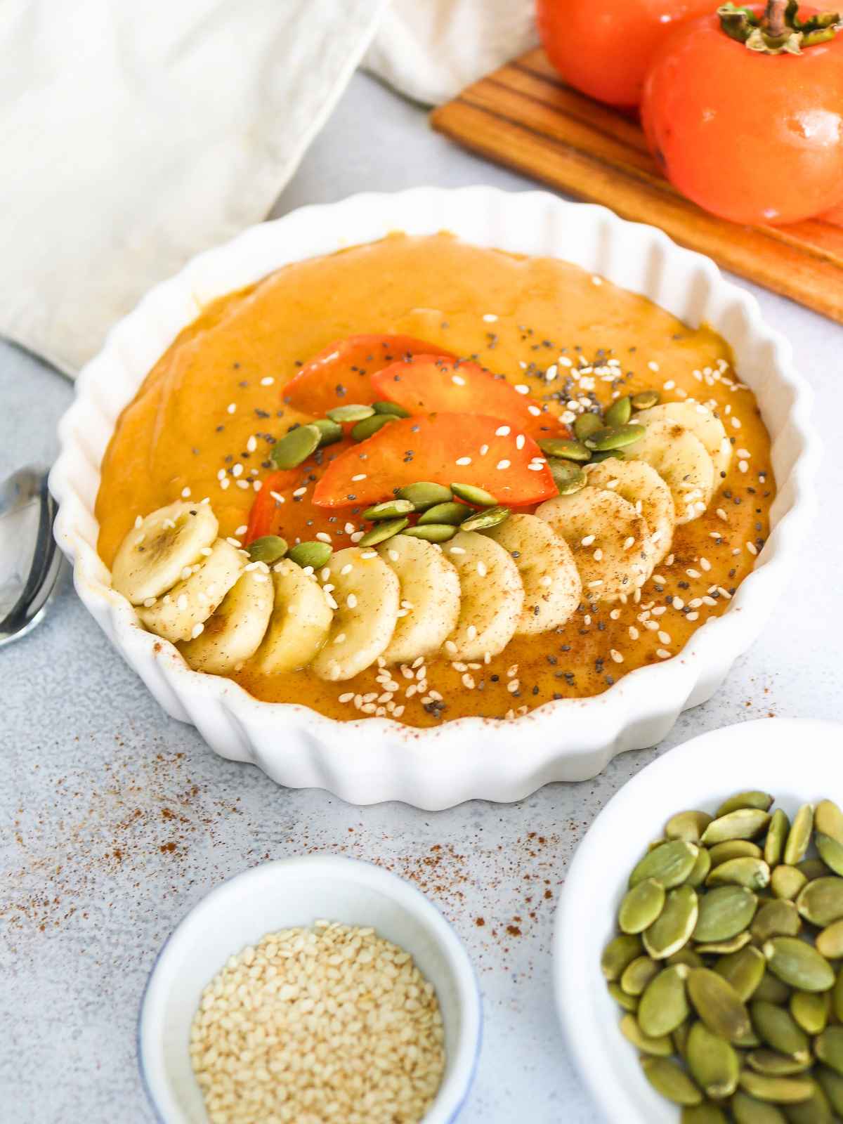 Persimmon smoothie an pumpkin seeds on side in a bowl.