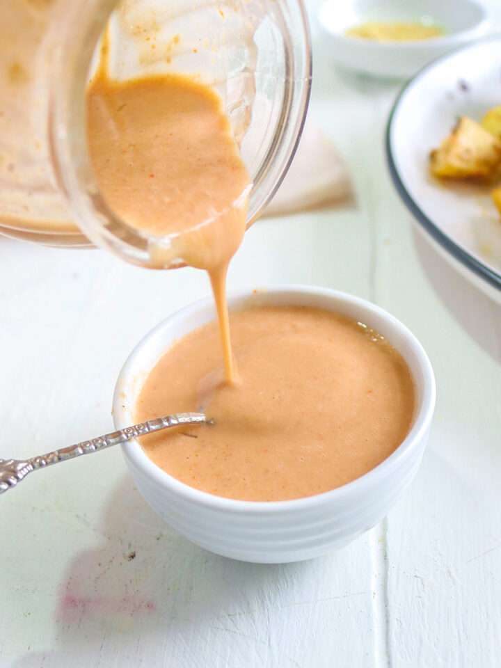 Pouring spicy tahini sauce in a bowl